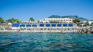 A beachside hotel with multiple blue-roofed structures, a sandy beach, and clear blue water. - Hotel Terme Tritone Resort & Spa (Forio)