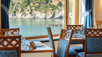 A dining area with a table set for two, overlooking a coastal landscape.