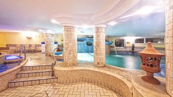 An indoor swimming pool area with tiled flooring, a hot tub, and a decorative urn.