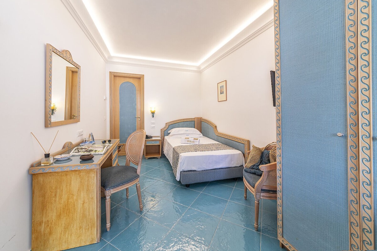 A hotel room with a bed, desk, chair, and a wardrobe.