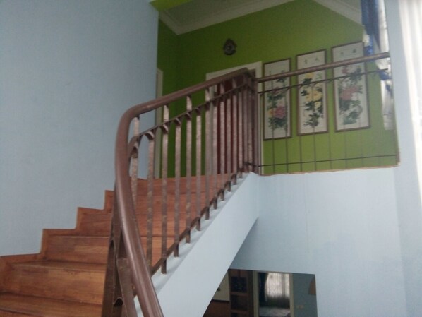 A wooden staircase with a metal handrail leading to a landing. - Kota Bunga D (Cipanas)