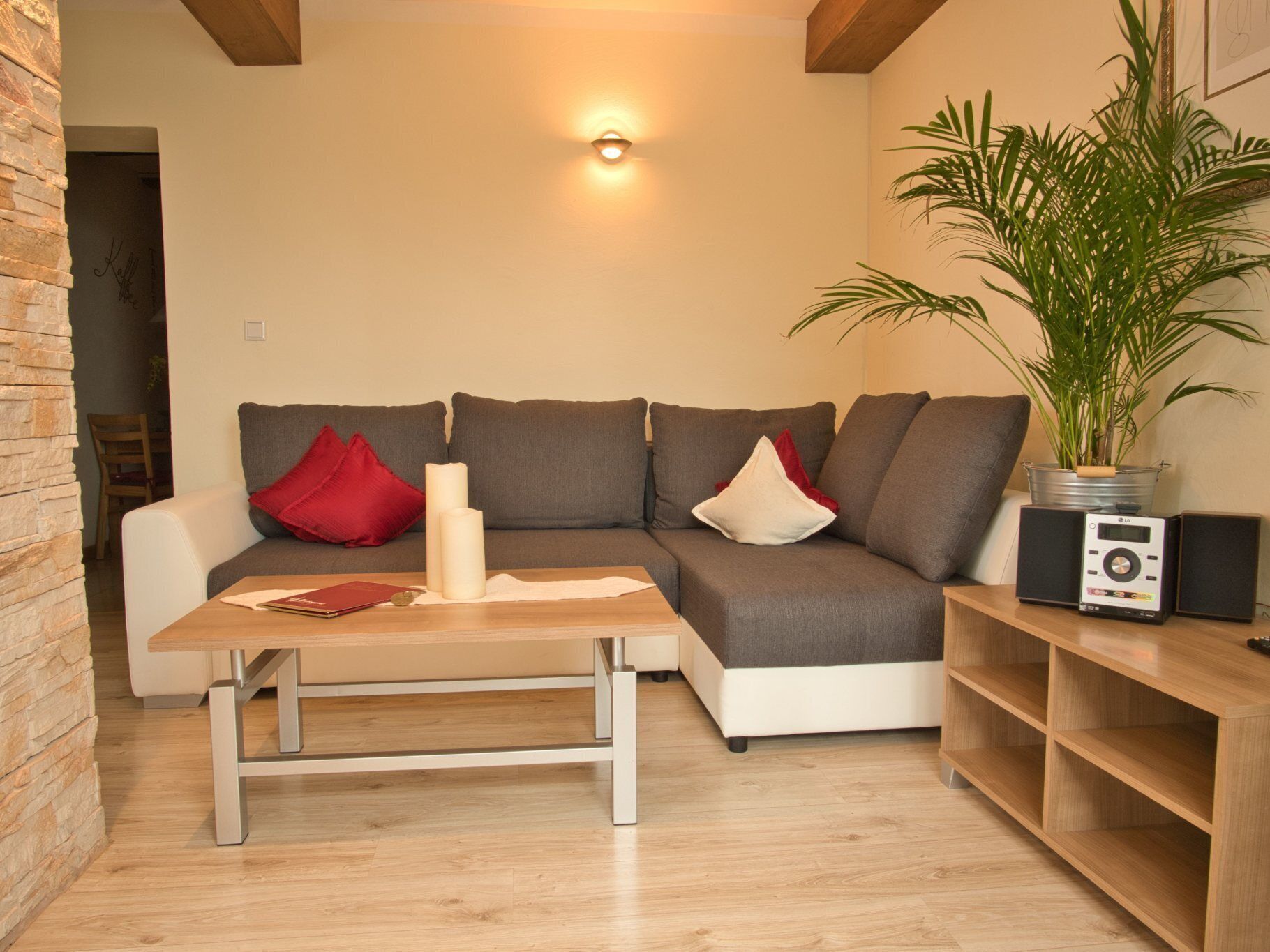 Una sala de estar moderna con un sofá gris, una mesa de centro de madera y una planta en maceta.