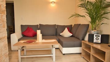 Una sala de estar moderna con un sofá gris, una mesa de centro de madera y una planta en maceta.