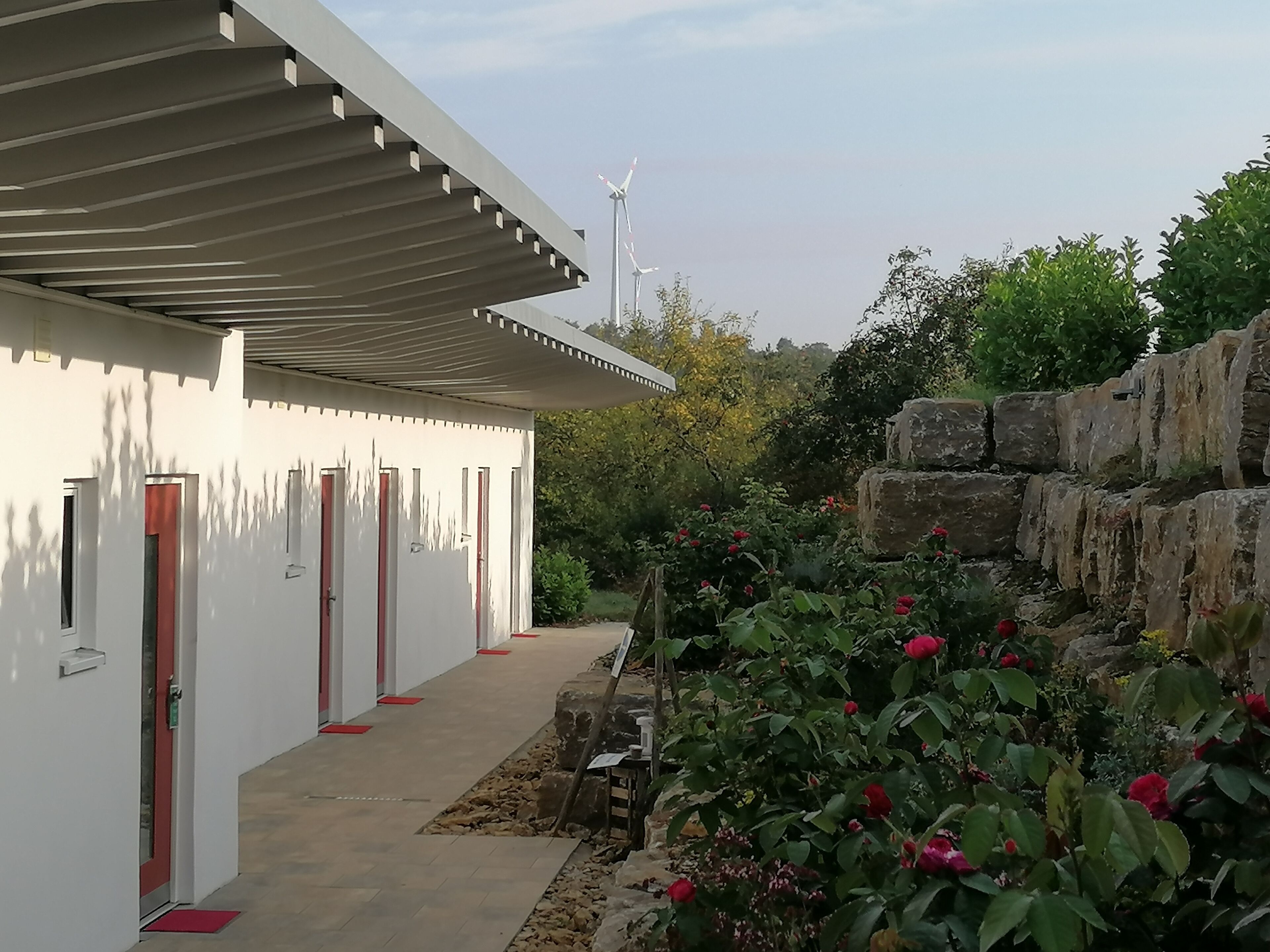 Un bâtiment doté d’une galerie couverte et d’un jardin agrémenté de fleurs rouges.