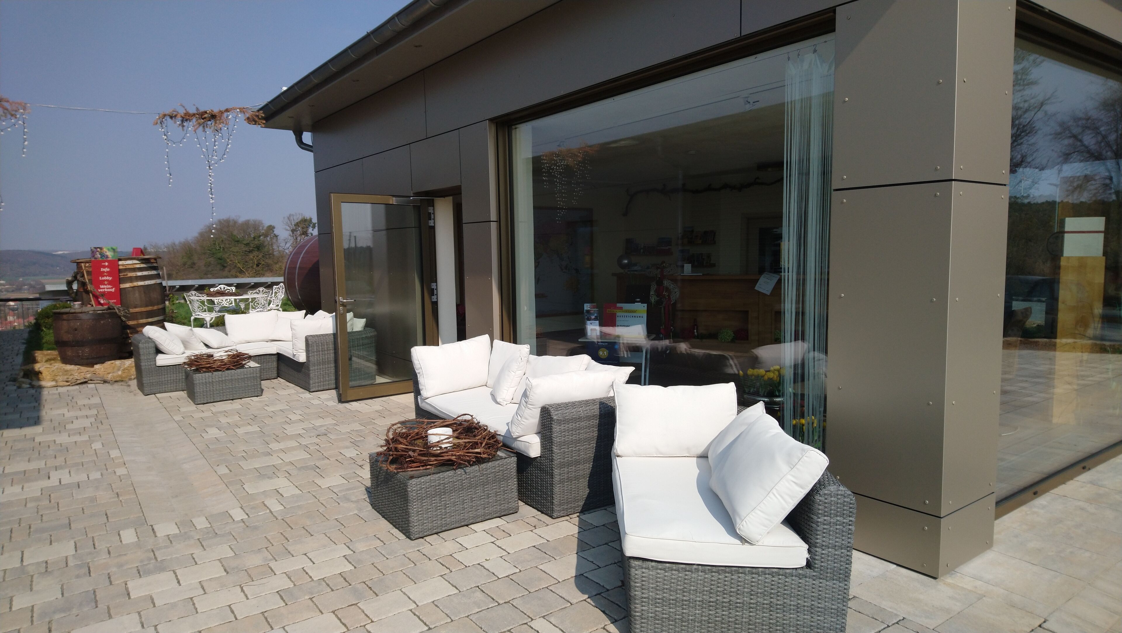 An outdoor seating area with wicker furniture and a glass door leading to a room.