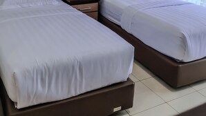 Hotellihuone, jossa on kaksi sänkyä, yöpöytä ja kaksi kehystettyä kuvaa seinällä.