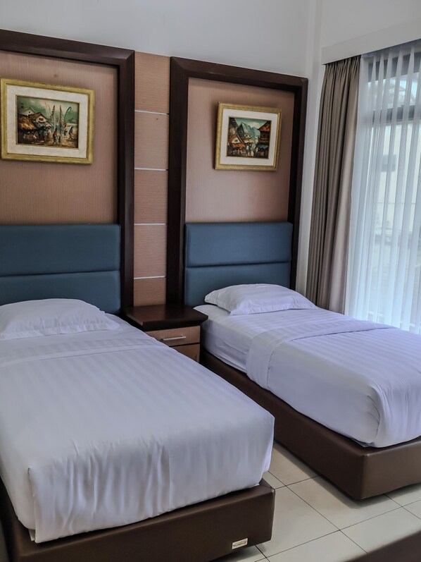 Habitación de hotel con dos camas, una mesita de noche y dos cuadros en la pared.