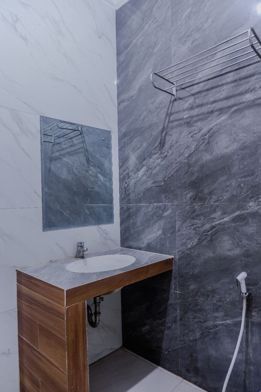 A bathroom with a marble vanity, a towel rack, and a shower hose.