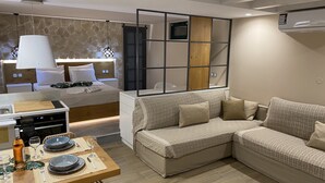 Een moderne hotelkamer met een zithoek, een bank, een televisie en een houten roomdivider.