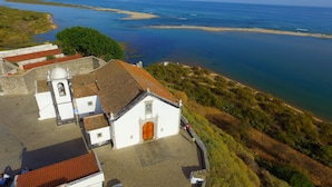 A coastal church with a red-tiled roof, a bell tower, and a paved courtyard. - Golden Club Cabanas (Tavira)
