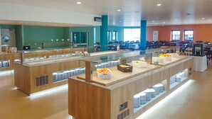 A spacious buffet area with multiple serving stations, a large window providing natural light, and a clean, modern design. - Golden Club Cabanas (Tavira)
