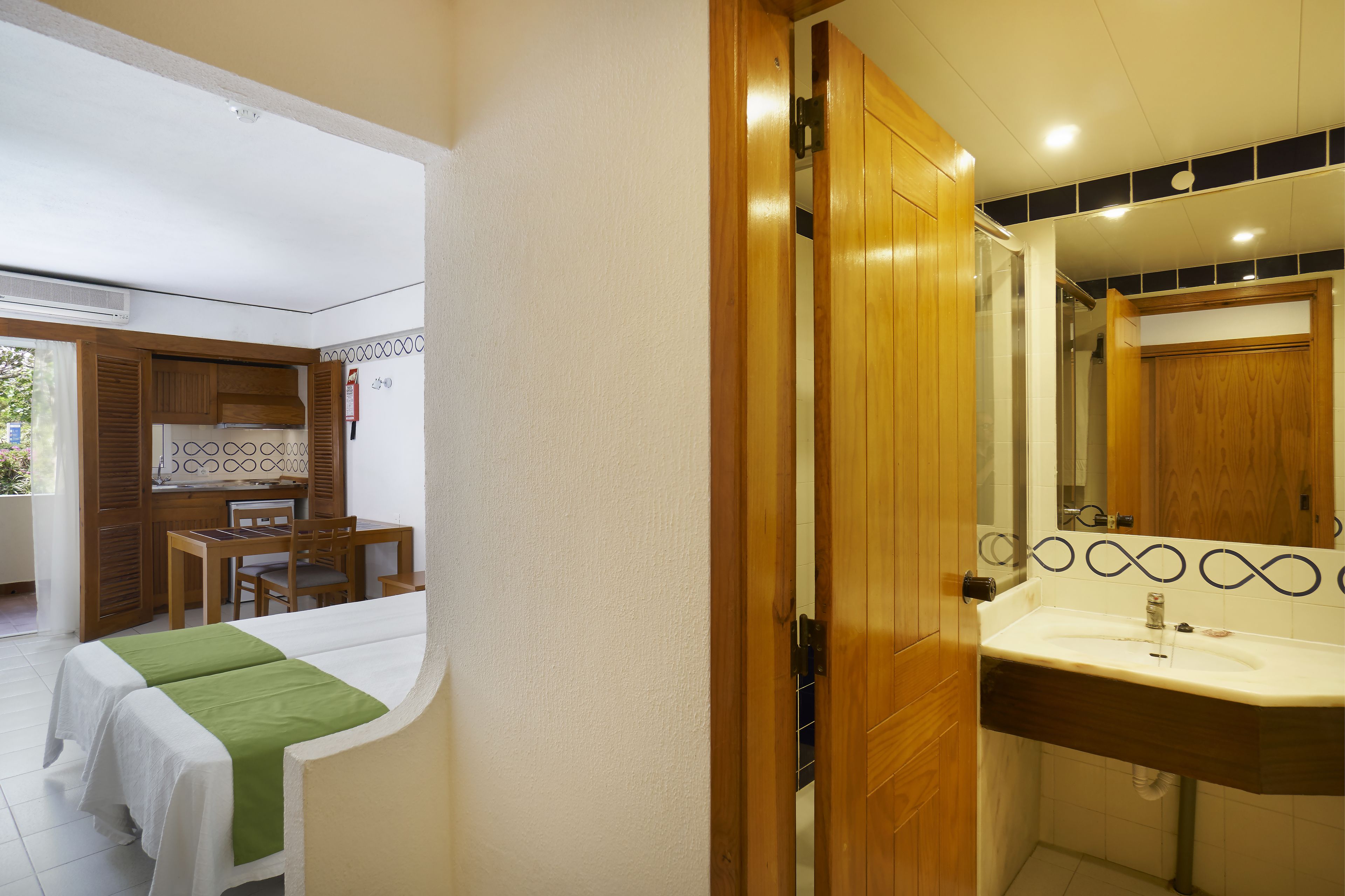A bathroom with a wooden door, a sink, and a mirror.