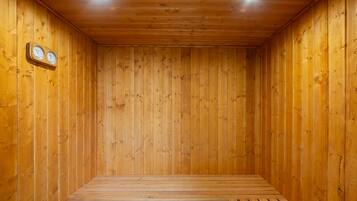 A wooden sauna with a bench, wooden walls, and two wall-mounted clocks.