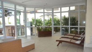 Un amplio espacio interior con ventanas grandes, una mesa de recepción y varios sillones.