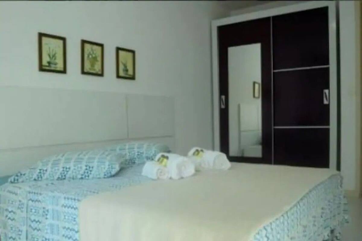 Une chambre à coucher avec un lit, une armoire et trois tableaux encadrés accrochés au mur.