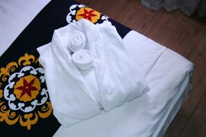 A neatly made bed with white linens and a decorative bedspread with floral patterns.
