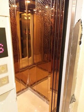 An elevator with a reflective interior and a visible control panel with buttons.