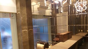 A modern bathroom with a marble vanity, a glass shower enclosure, and a chandelier. - The Fountain Inn - Fort (Mumbai)