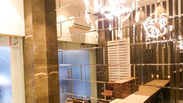 A modern bathroom with a marble wall, a long counter, and a hanging light fixture. - The Fountain Inn - Fort (Mumbai)