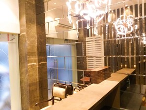 A modern bathroom with a marble wall, a long counter, and a hanging light fixture.