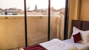 A hotel room with a bed, a telephone, and a view of the cityscape. - The Fountain Inn - Fort (Mumbai)