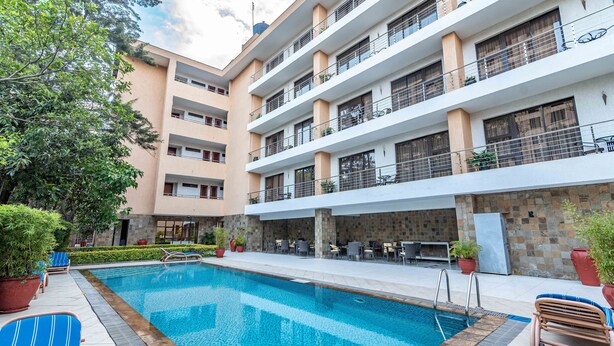 A swimming pool with lounge chairs and a patio area, surrounded by a multi-story building with balconies. - Lenana Suites (Nairobi)