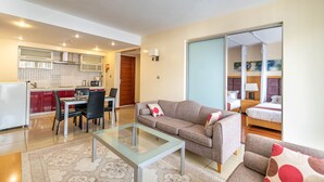 A modern apartment with a dining area, kitchenette, sofa, and a bedroom with a sliding door. - Lenana Suites (Nairobi)