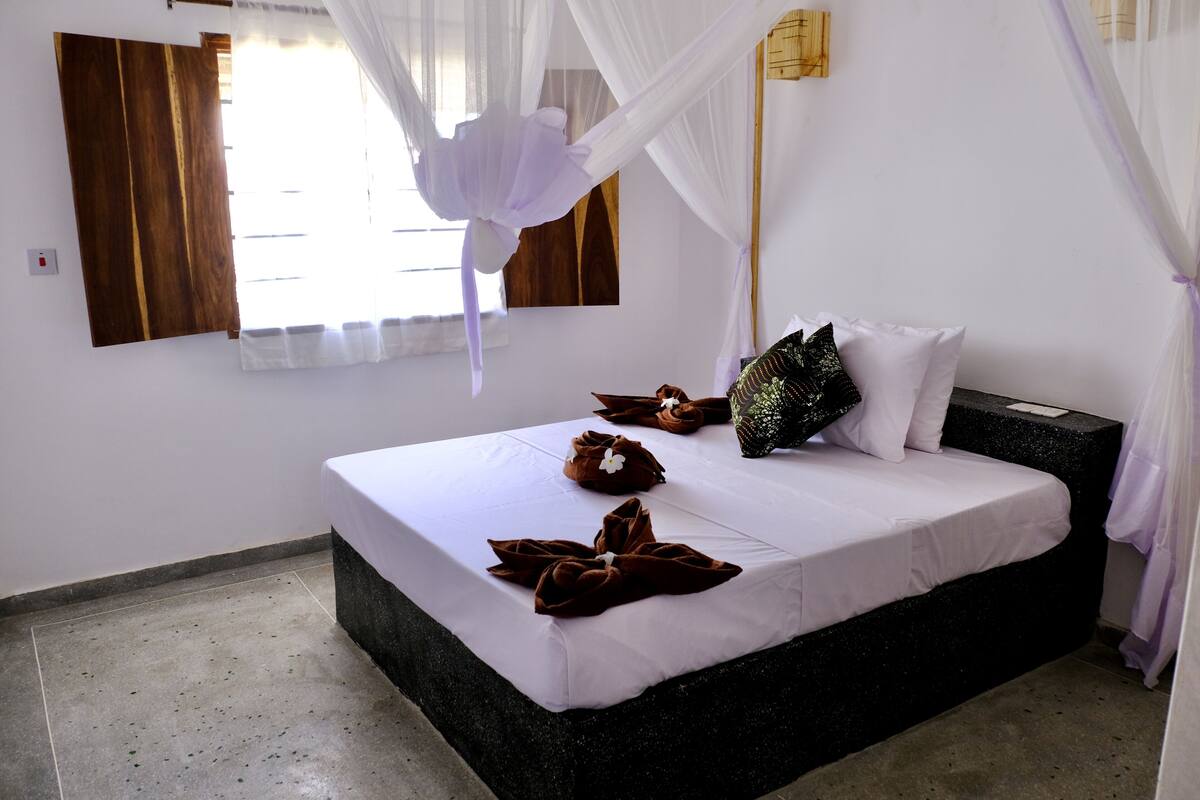 A neatly made bed with white linens and brown towels arranged on it.