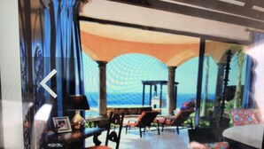 Una habitación con vista al océano, una mesa con sillas y un sofá.