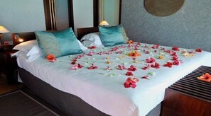 A neatly made bed with a white bedspread, teal pillows, and a floral arrangement on the bed.