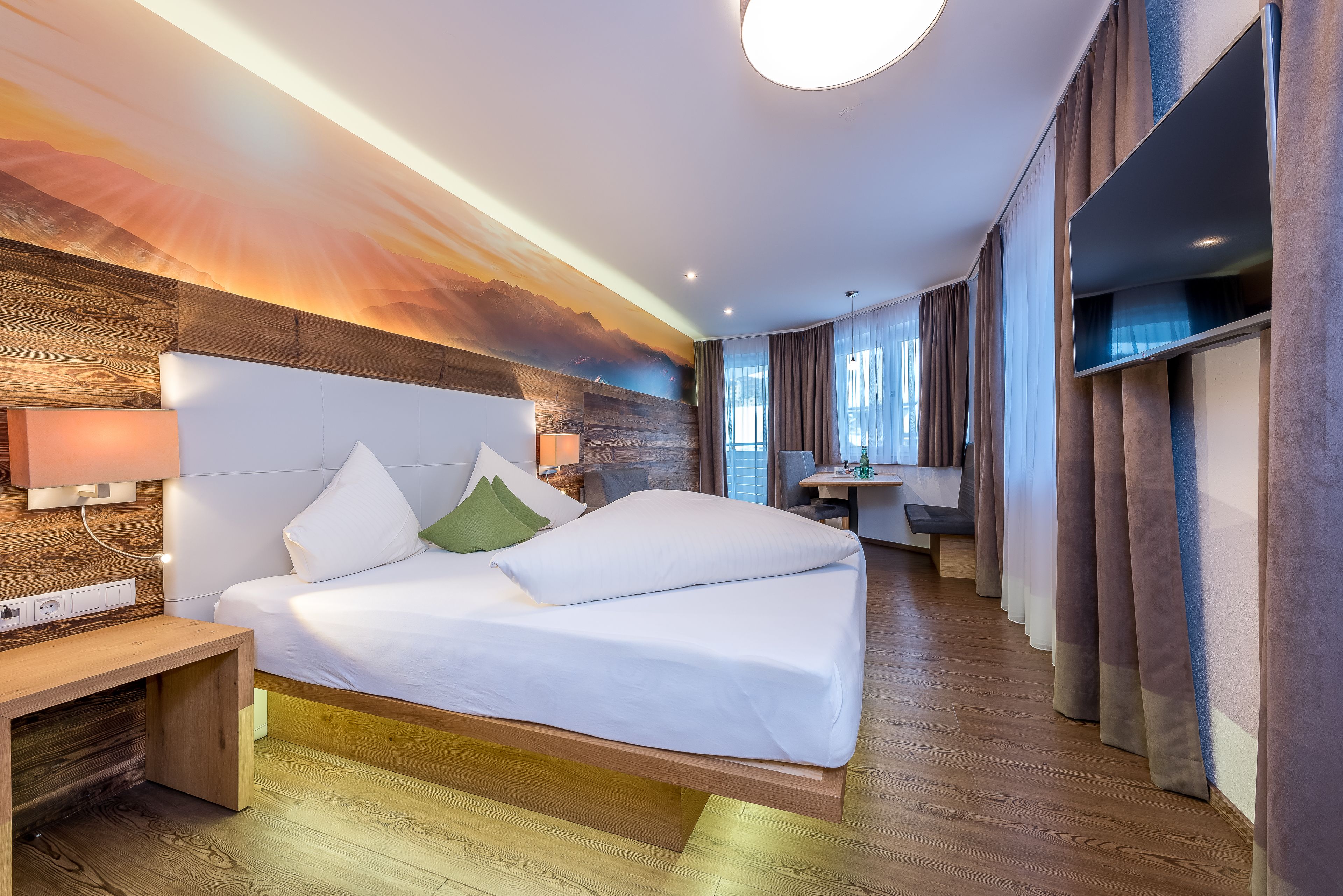 A modern hotel room with a wooden headboard, a bed with white linens, a bedside table, and a wall mural.