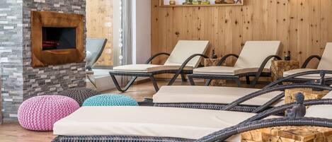 Un espace détente avec des fauteuils et des poufs en osier, une cheminée et des éléments de décoration en bois sur les murs.