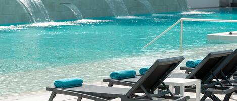 Zona de piscina con sillones de descanso y una cascada.