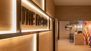 Un interior moderno con un mostrador de recepción de madera y un cartel que dice 'THE FACTORY'.