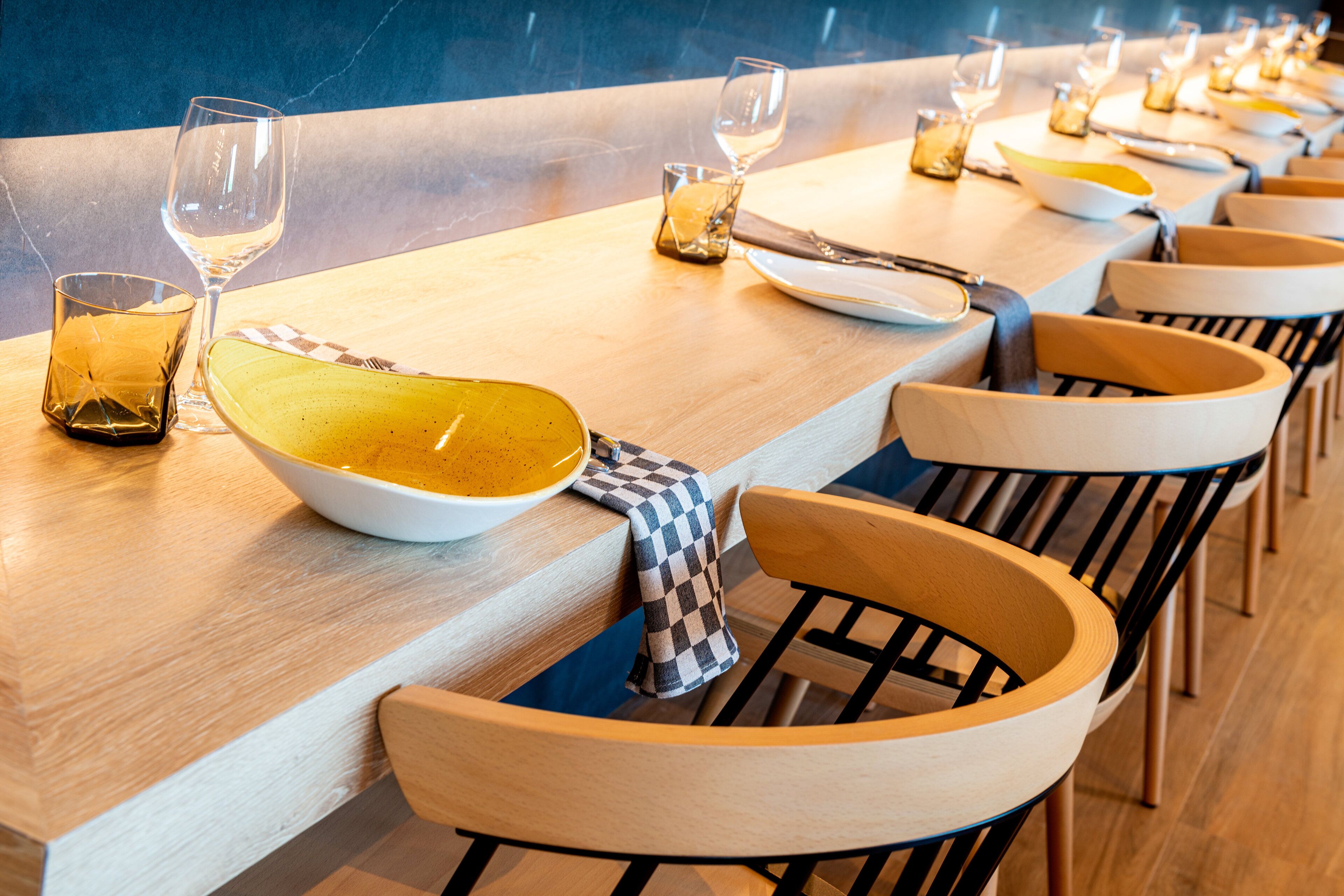 A restaurant with a long wooden table set with plates, glasses, and cutlery.