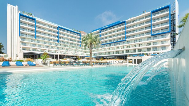 Un hotel con varios pisos, piscina y una cascada.