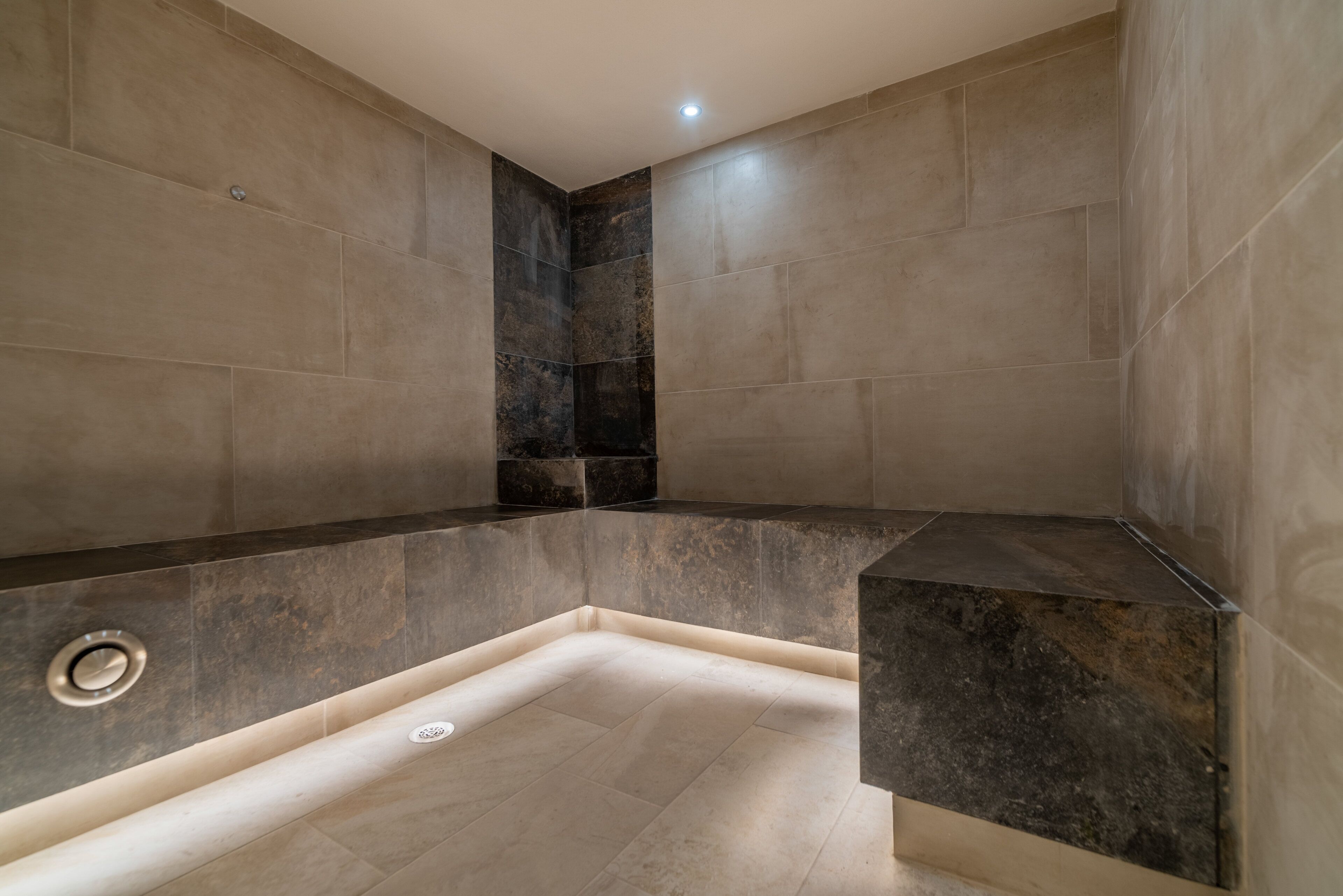 A modern bathroom with a corner shower, tiled walls, and a built-in bench.