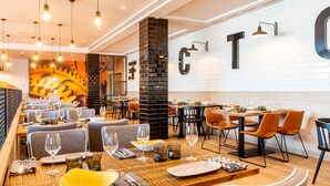 Un restaurante moderno con varias mesas, sillas y lámparas colgantes.
