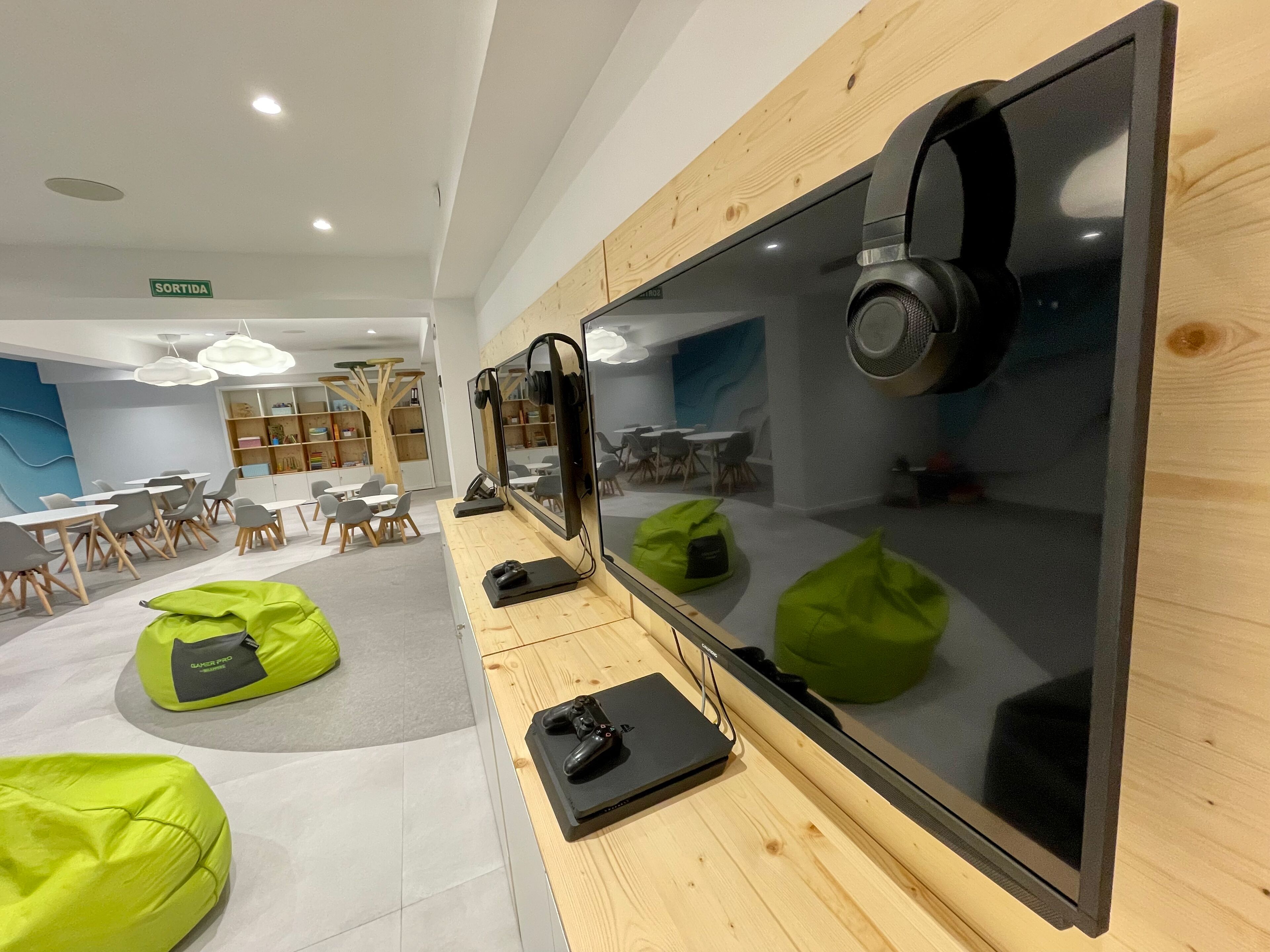 A modern room with a large flat-screen TV, gaming chairs, and bean bags.