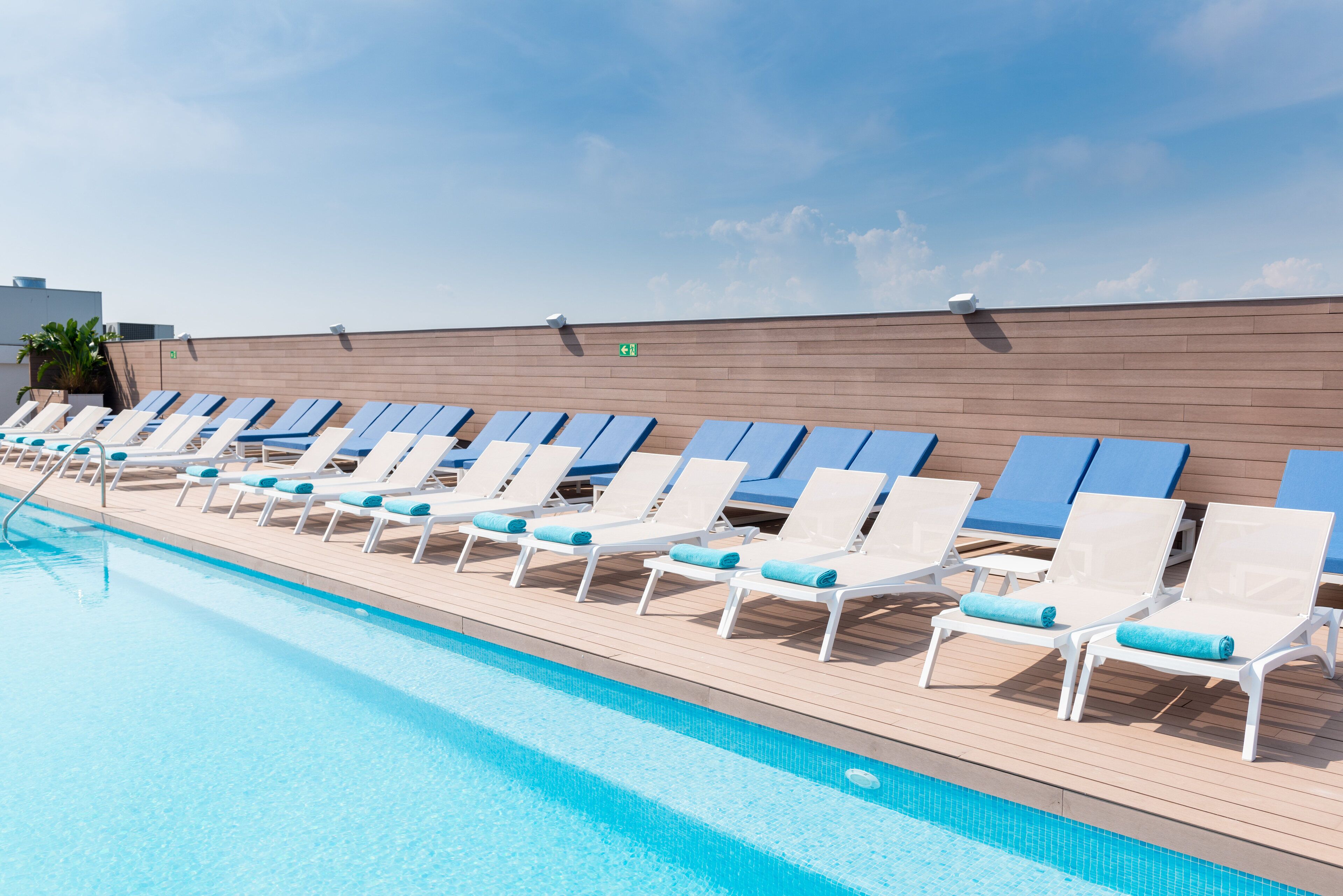 A poolside area with rows of sun loungers and a wooden deck.