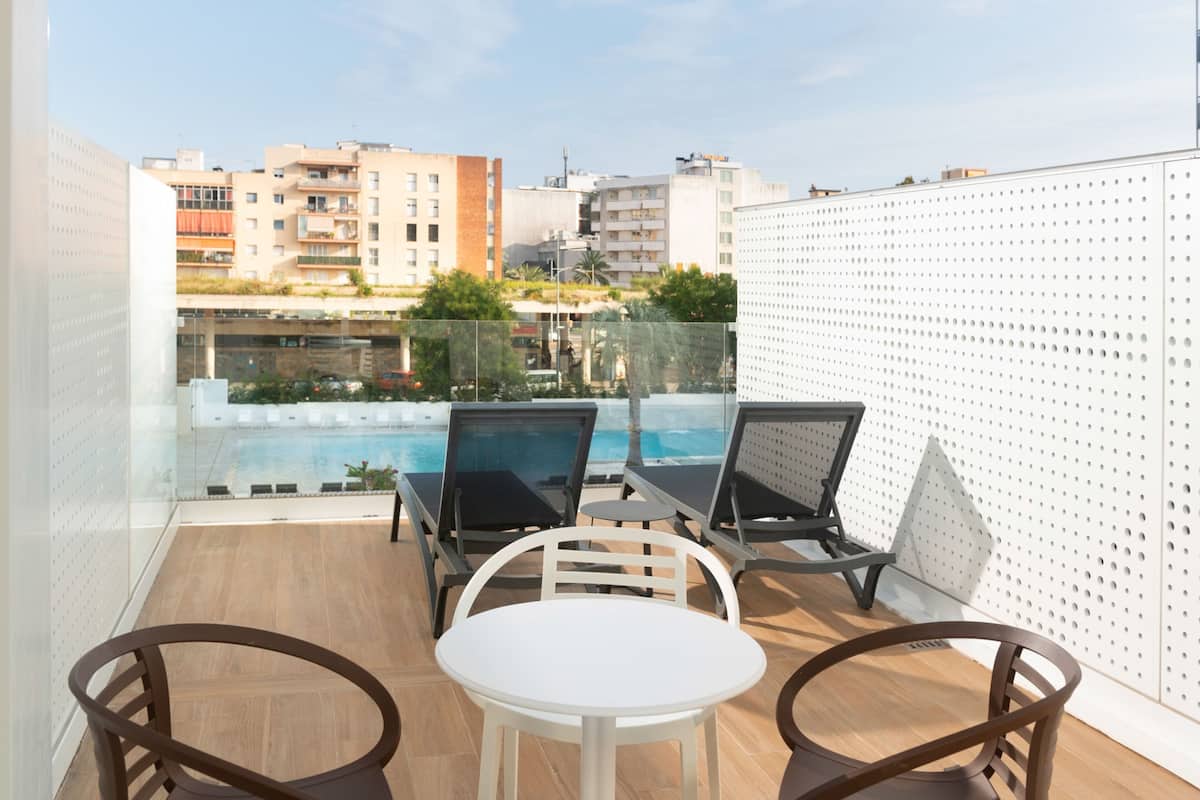 Un balcon avec une piscine, deux chaises longues et une table.