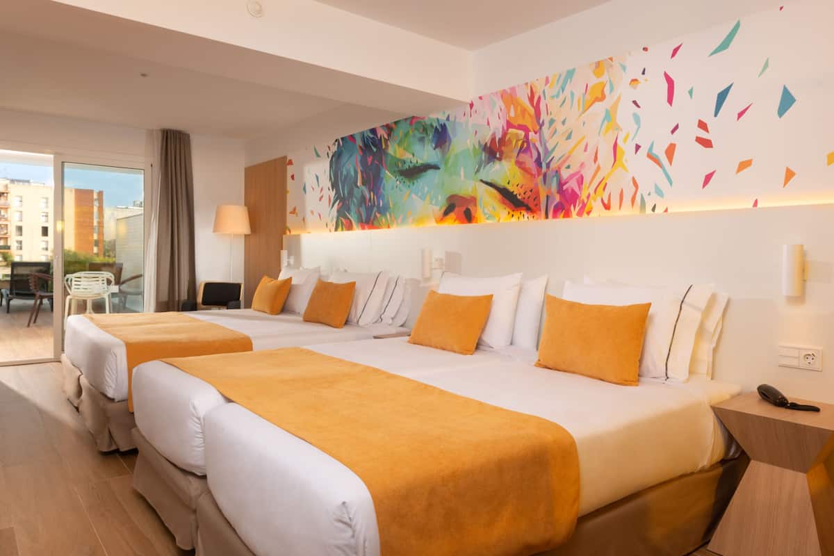 Une chambre d’hôtel avec deux lits, une peinture abstraite aux couleurs vives accrochée au mur et une vue sur la ville par la fenêtre.