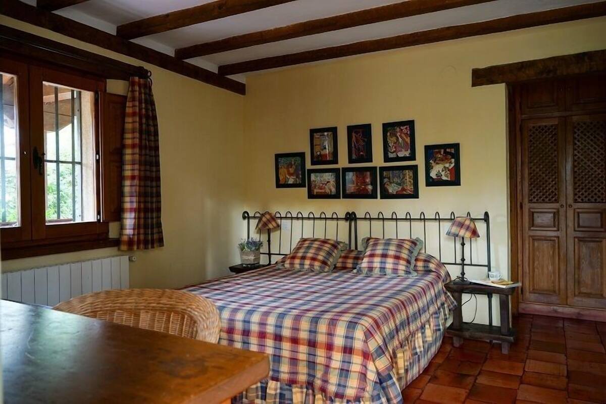 Une chambre confortable avec un lit, une table et une fenêtre avec des rideaux.