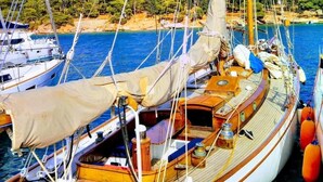 A sailboat docked at a marina with a flag reading "Ganimede Hotel".