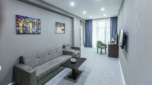 A modern living room with a grey sofa, a coffee table, and two paintings on the wall. - Parallel Hotel (Baku)