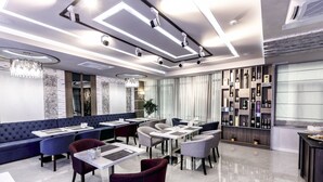 A modern restaurant with a mix of seating options including booths and tables, a wine display, and a chandelier. - Parallel Hotel (Baku)