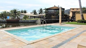 Una piscina con una escalera metálica, rodeada de baldosas de piedra.