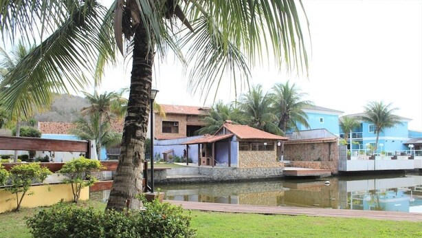 Un resort con piscina, palmeras y edificios con tejados azules y rojos.