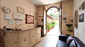 Una habitación con una recepción, un sofá y vistas a un patio con plantas en macetas.