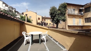 A small outdoor balcony with a table and chairs, surrounded by buildings with balconies and windows. - Hotel  Rita  Major (Florence)